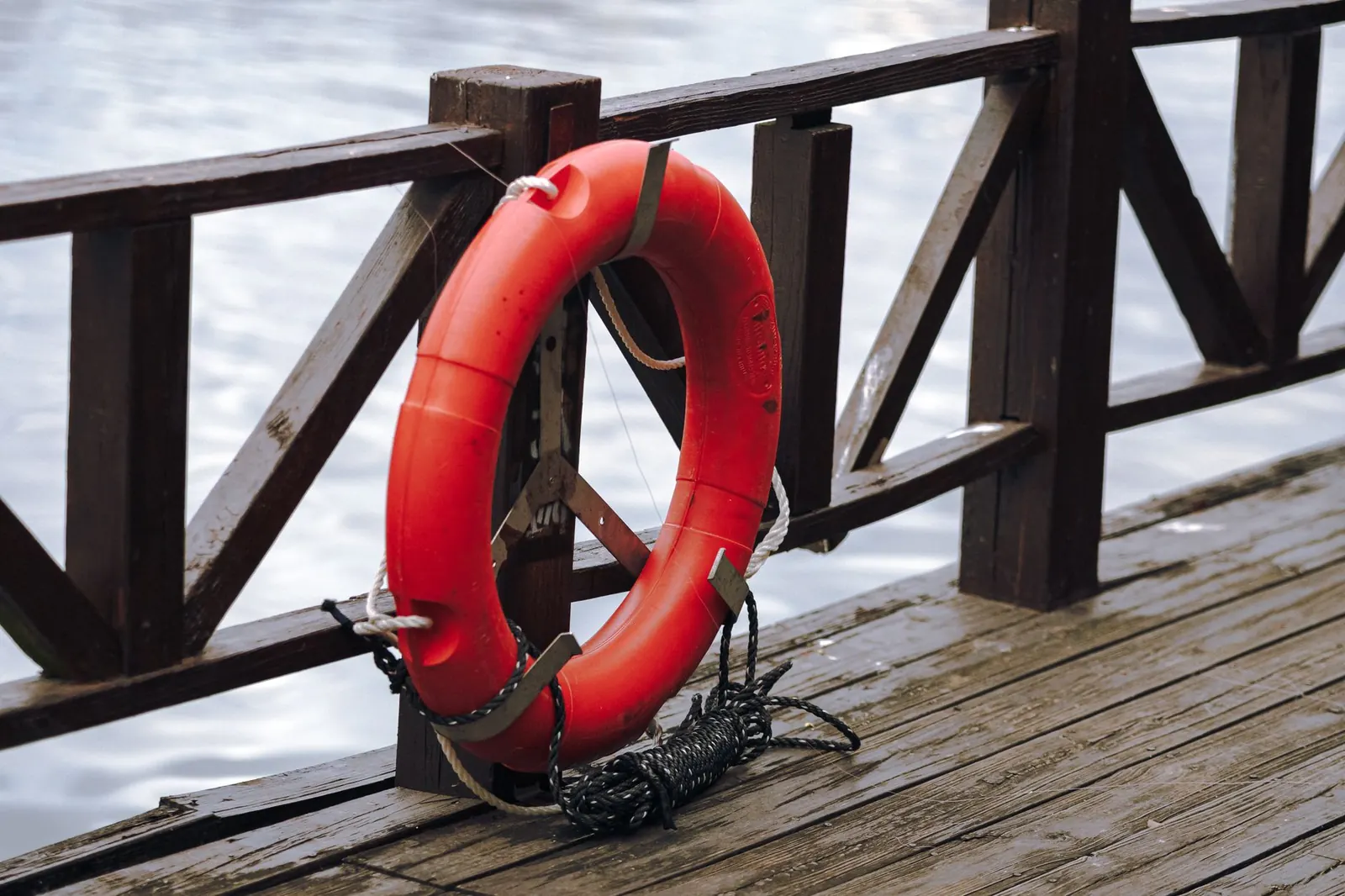 Red life ring hanging on a wooden dock railing